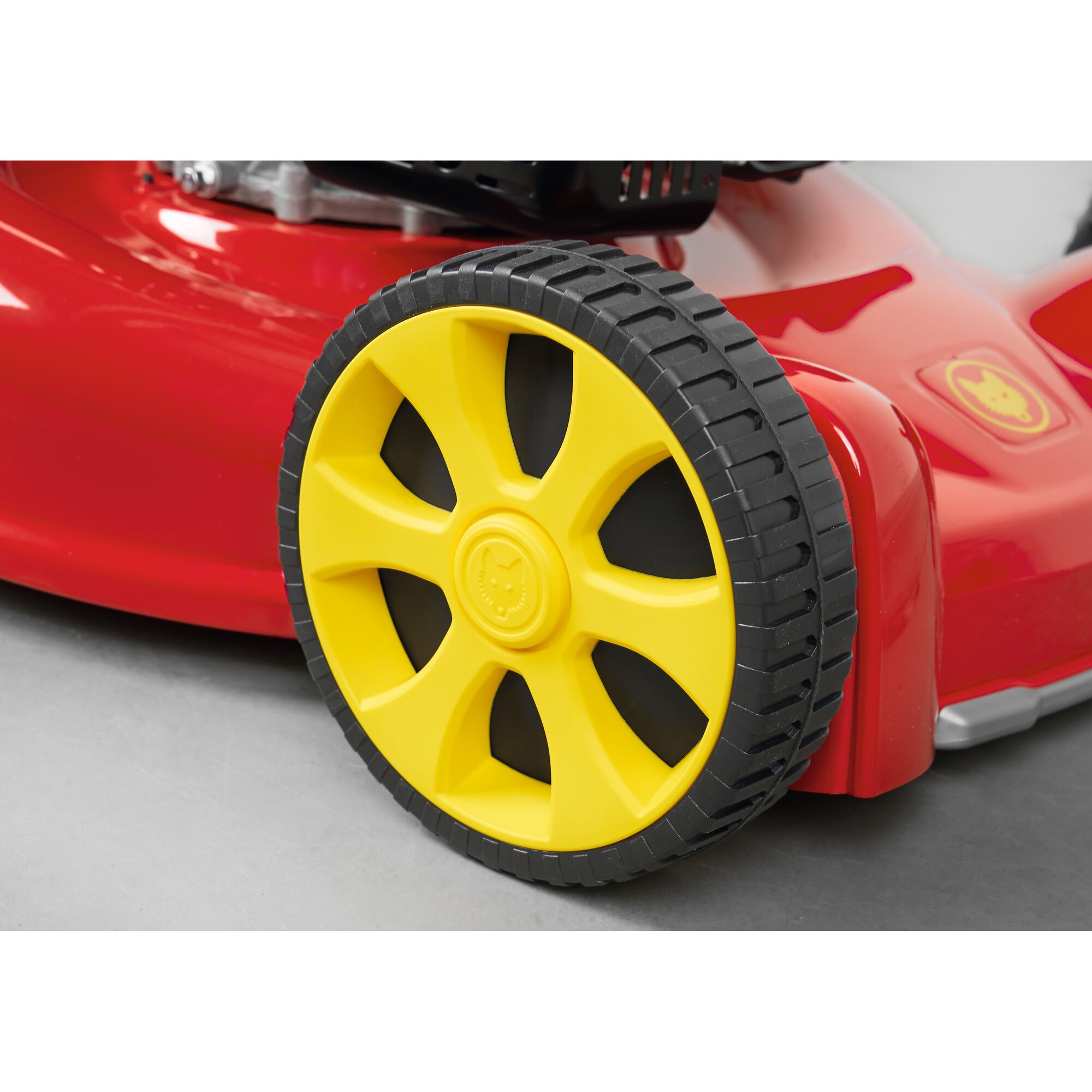 Close-up of a yellow and black wheel on a red lawn mower.