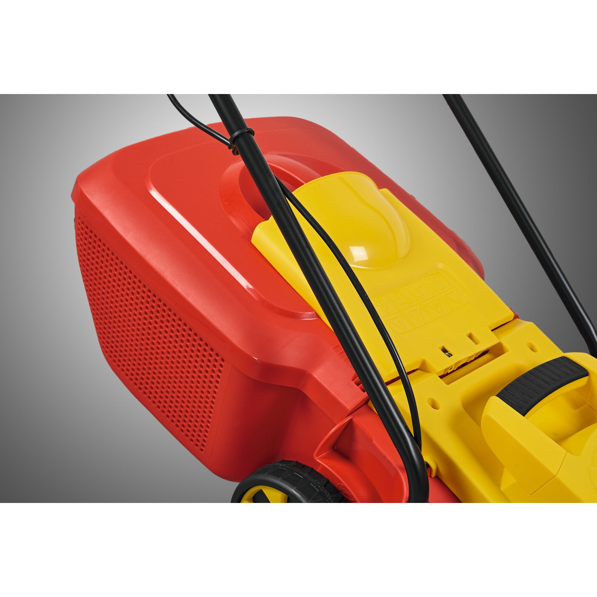 Close-up of a red and yellow lawn mower viewed from the rear side, showing the grass collection box, handle, and wheel.