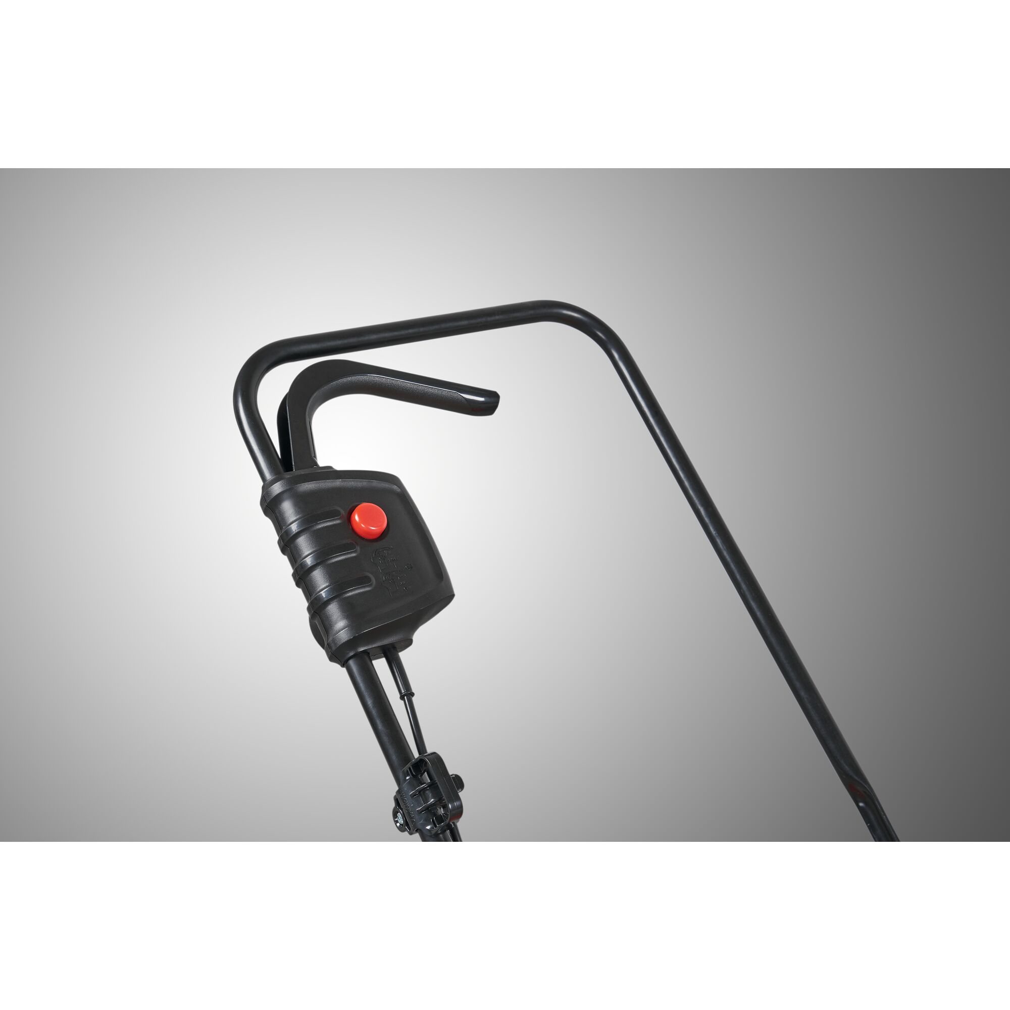 Close-up view of a black metal handle with a control box and red button, likely part of a garden tool or machine, against a grey gradient background.