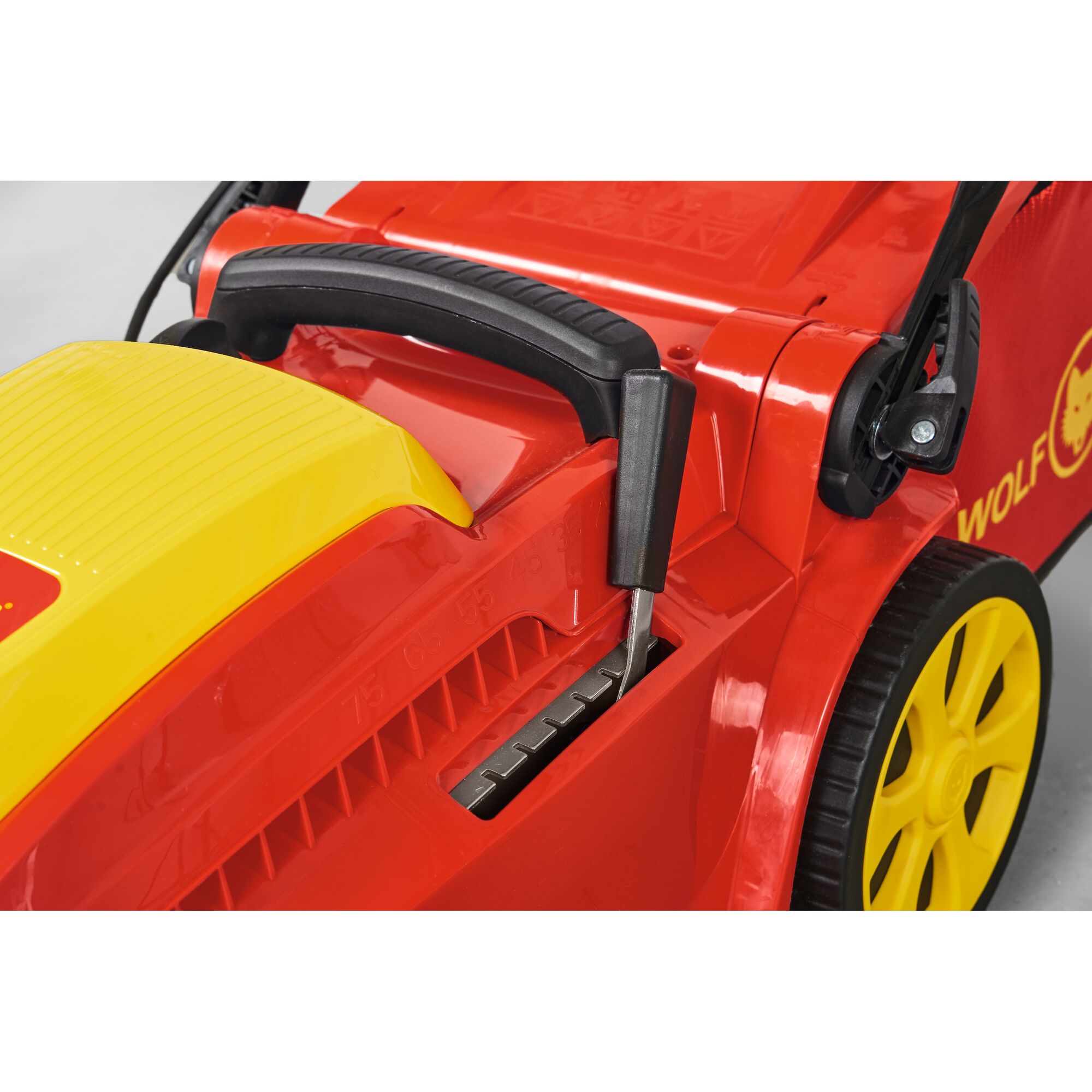 Close-up of a red and yellow lawn mower with adjustable height control lever and yellow wheels.