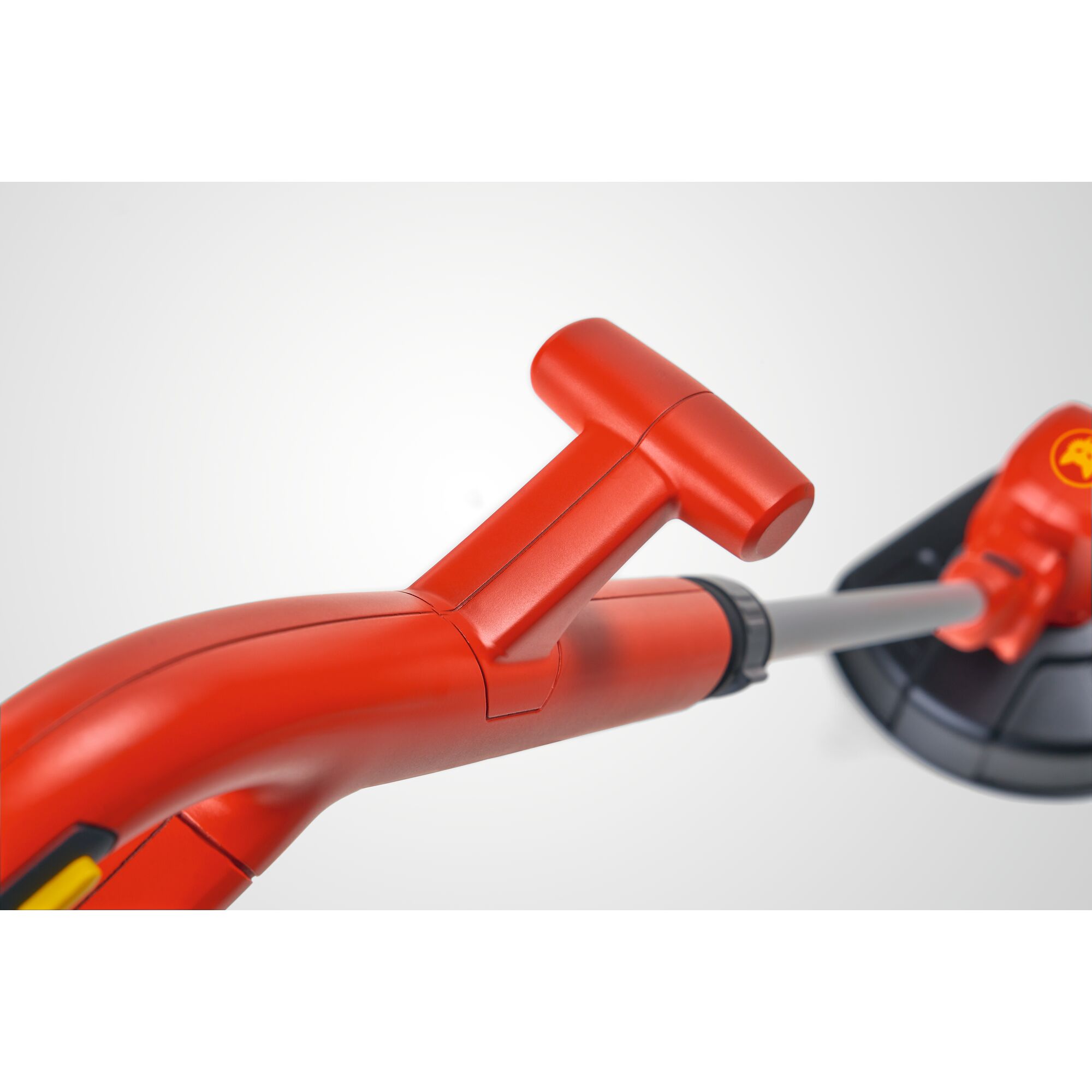 Close-up view of a red handle and shaft of a WOLFGarten garden trimmer, with a black protective guard visible in the background.