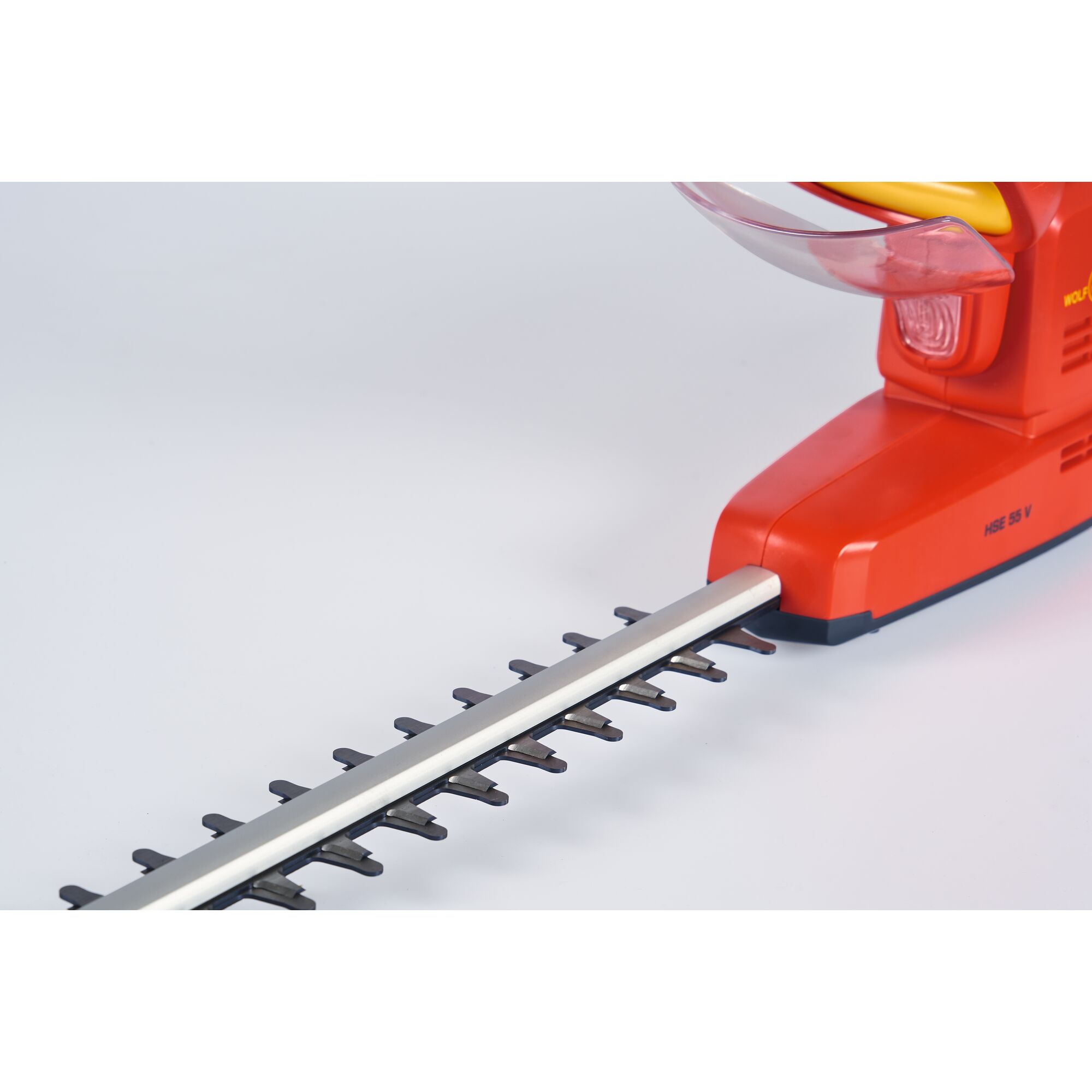 Close-up of an electric hedge trimmer with a red and yellow body and a silver blade, photographed against a plain white background.