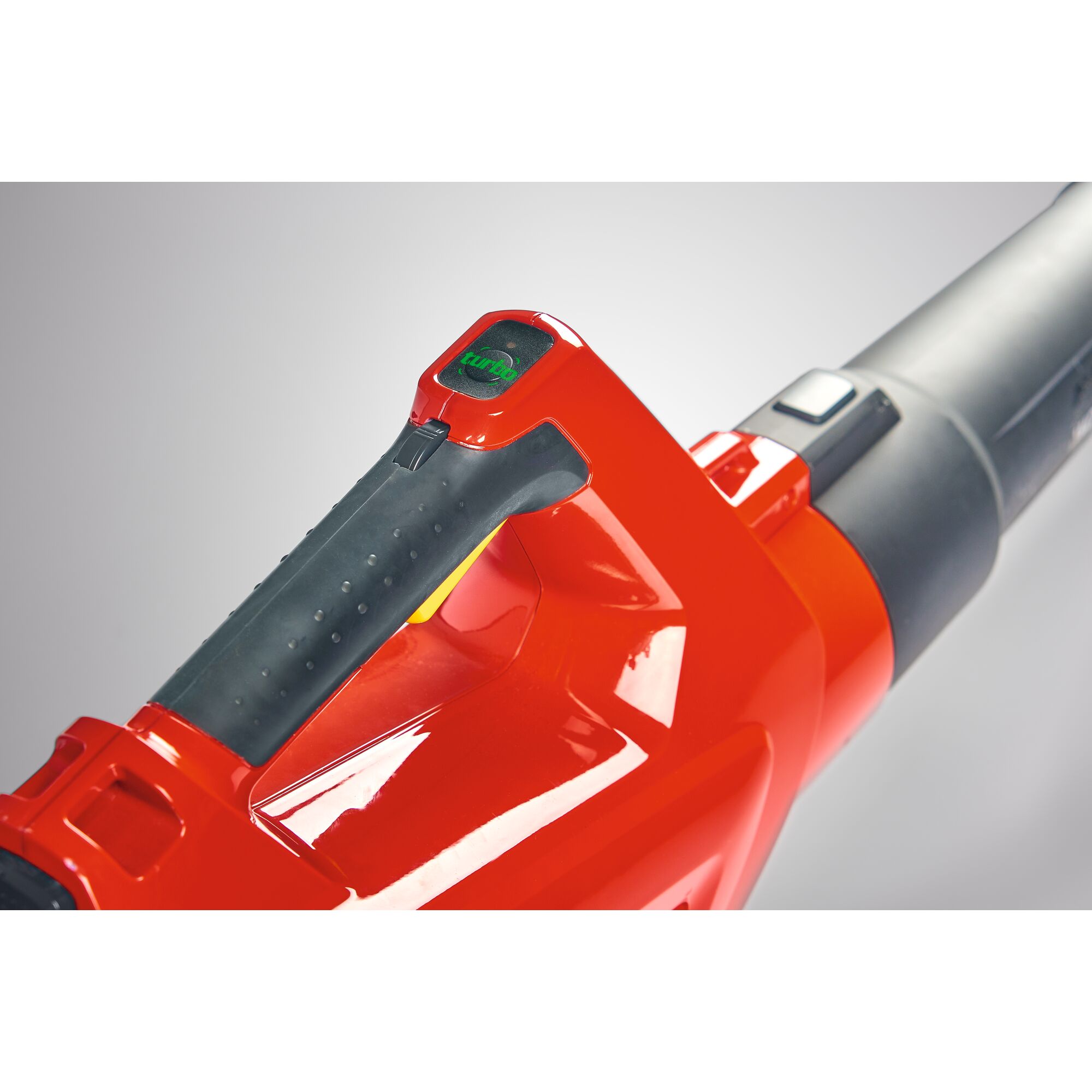 Close-up of a red and black handle of a garden leaf blower, showing the control buttons and grip, with modern design details.