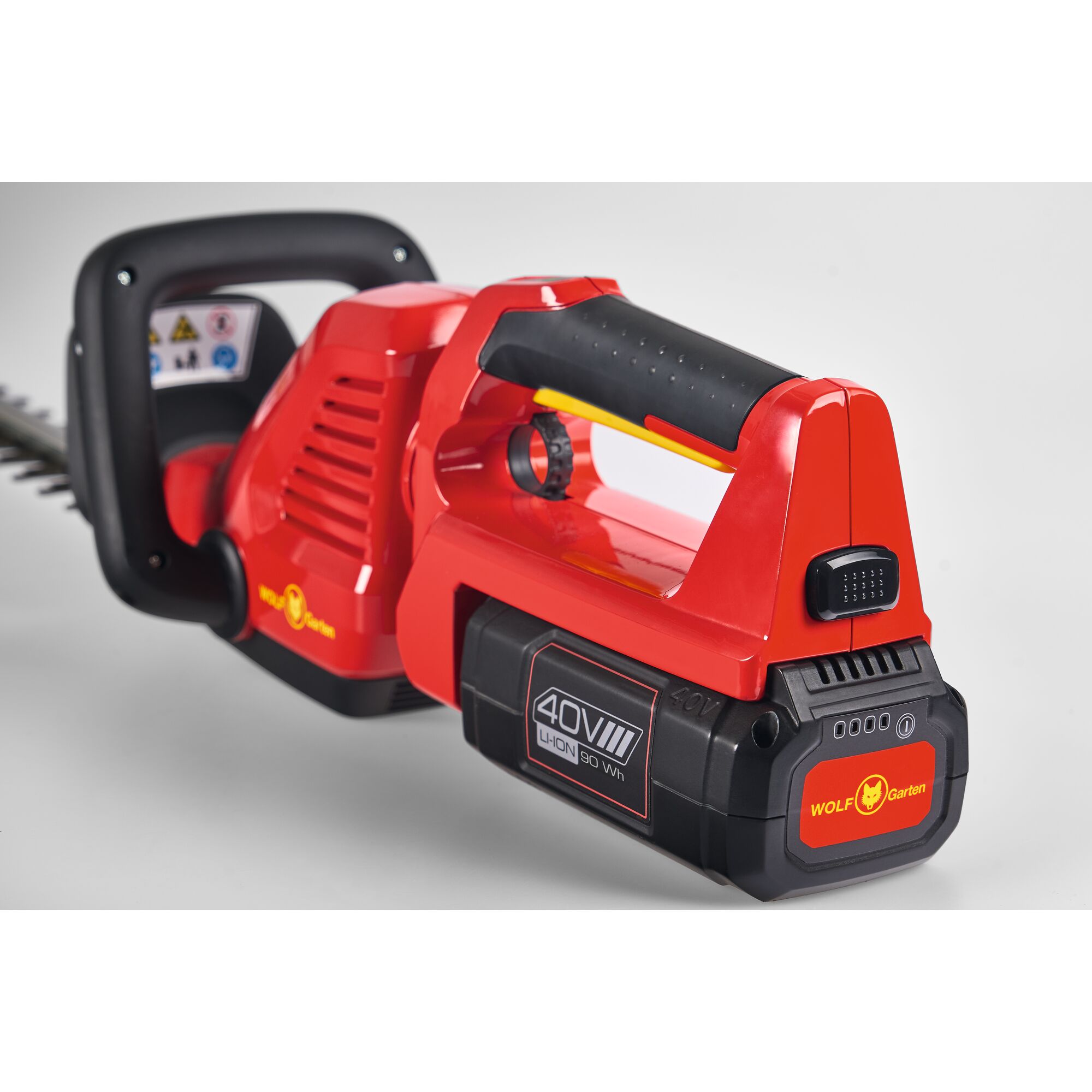 Close-up view of a WOLFGarten 40V lithium-ion cordless hedge trimmer, featuring a red and black ergonomic handle and visible battery pack.
