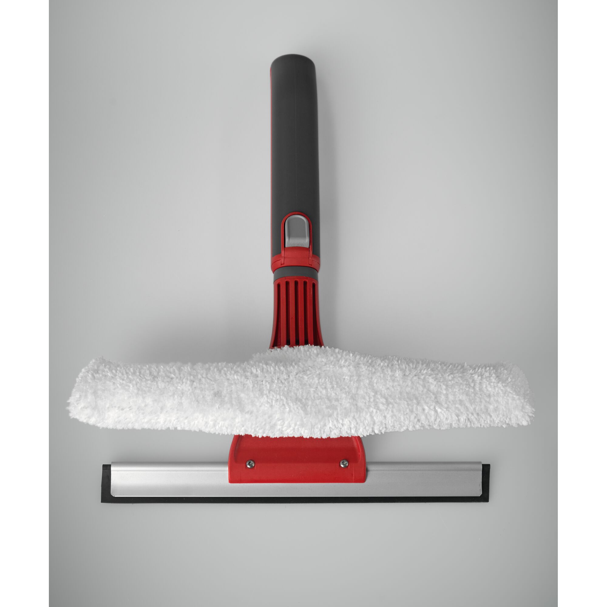 A window cleaning tool with a red and black handle, featuring a white microfiber pad above a metal and rubber squeegee blade.