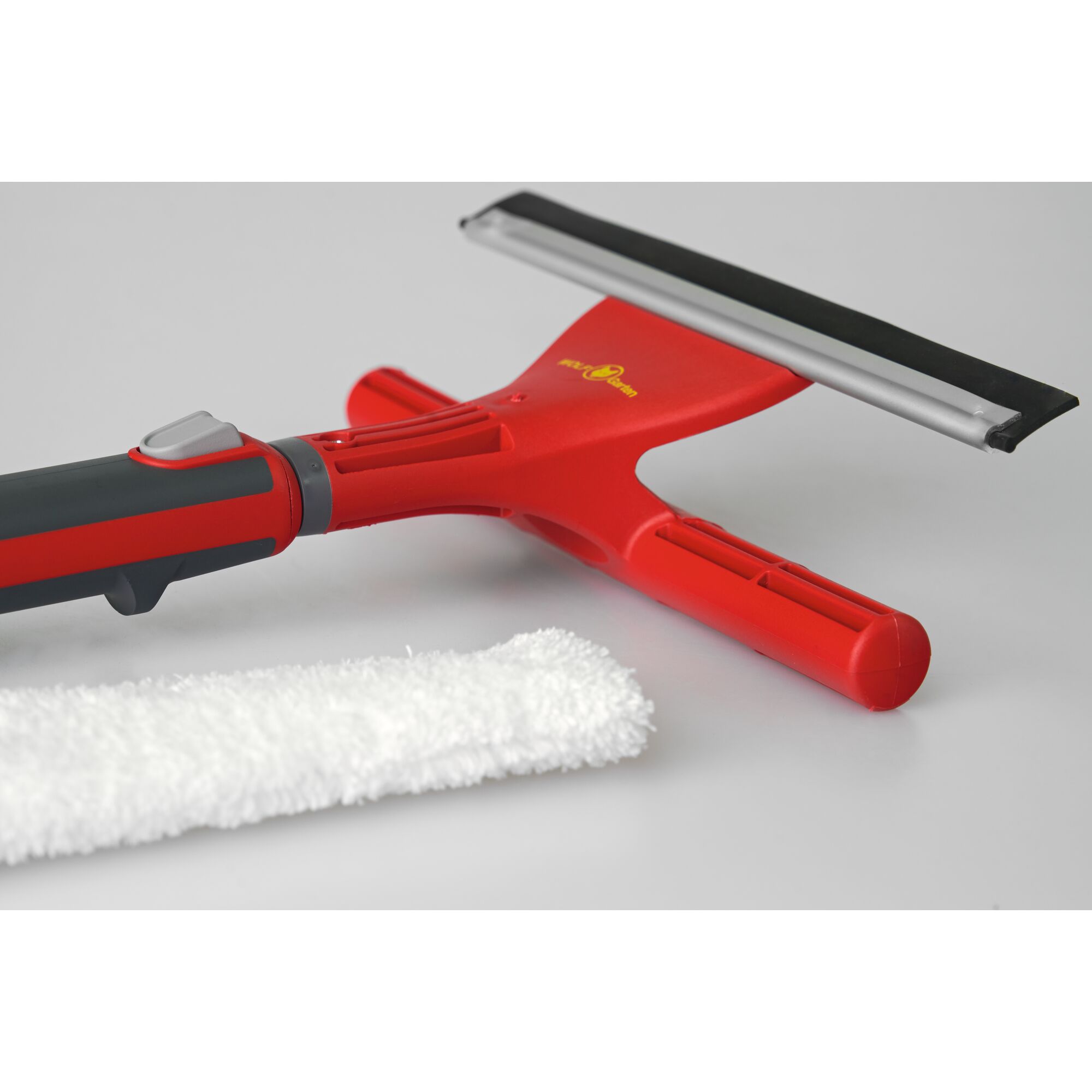 A red and black window squeegee with a detachable microfiber cleaning pad, shown on a light grey surface.