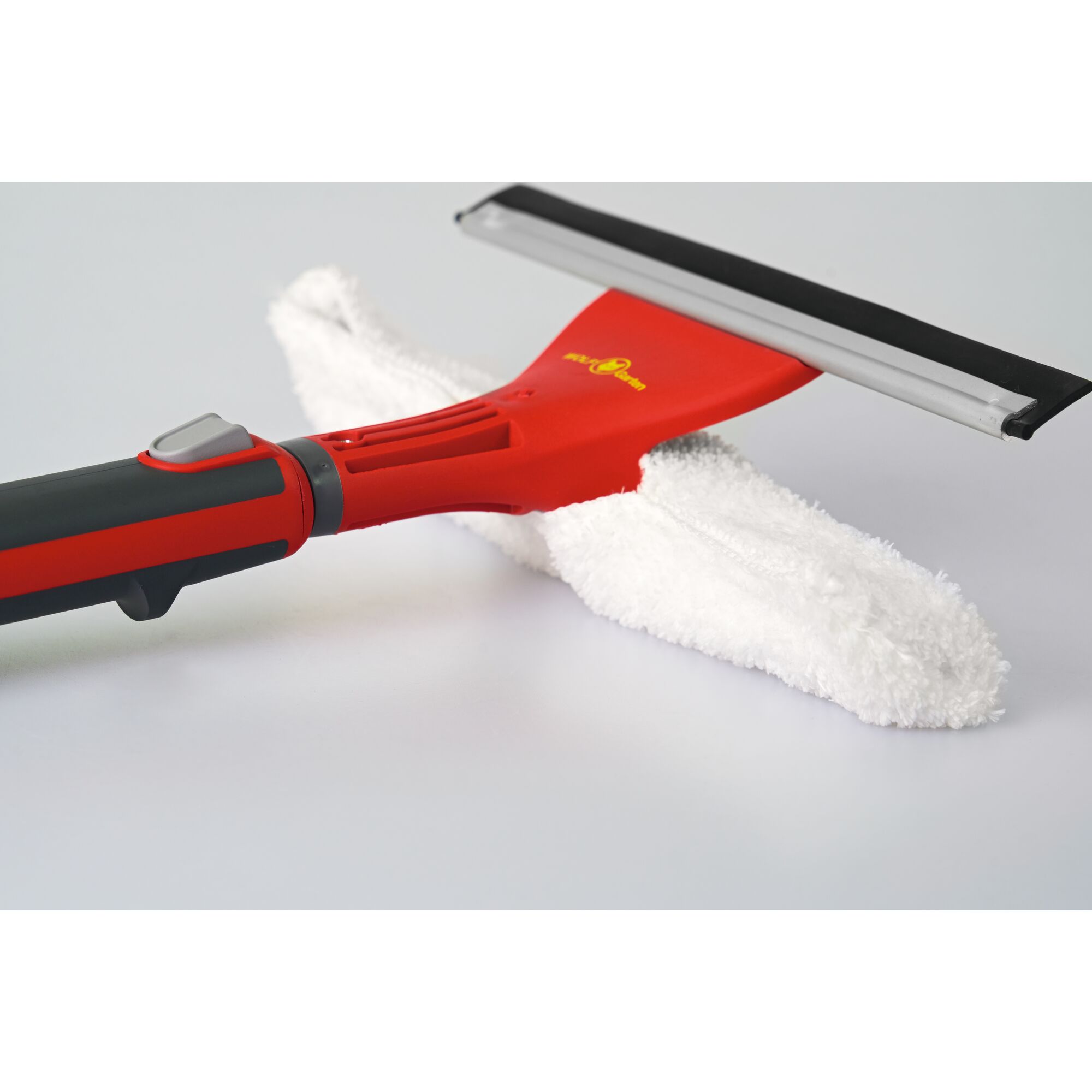 Close-up of a WOLFGarten window cleaning tool with a red handle, black and silver squeegee blade, and white microfiber cloth attachment.