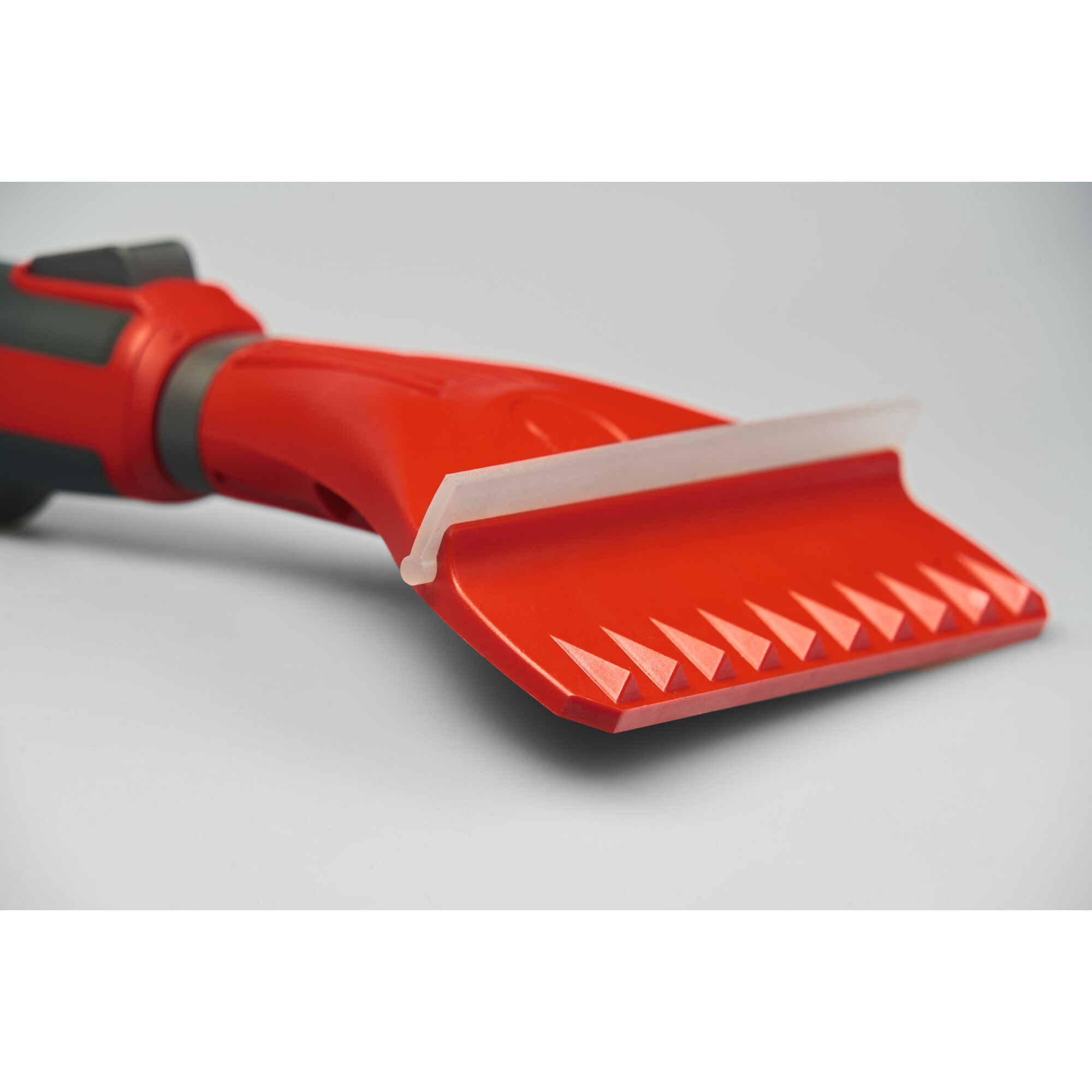 Close-up view of a red WOLFGarten hand tool with a serrated plastic blade and a white scraper edge, suitable for gardening or cleaning tasks.