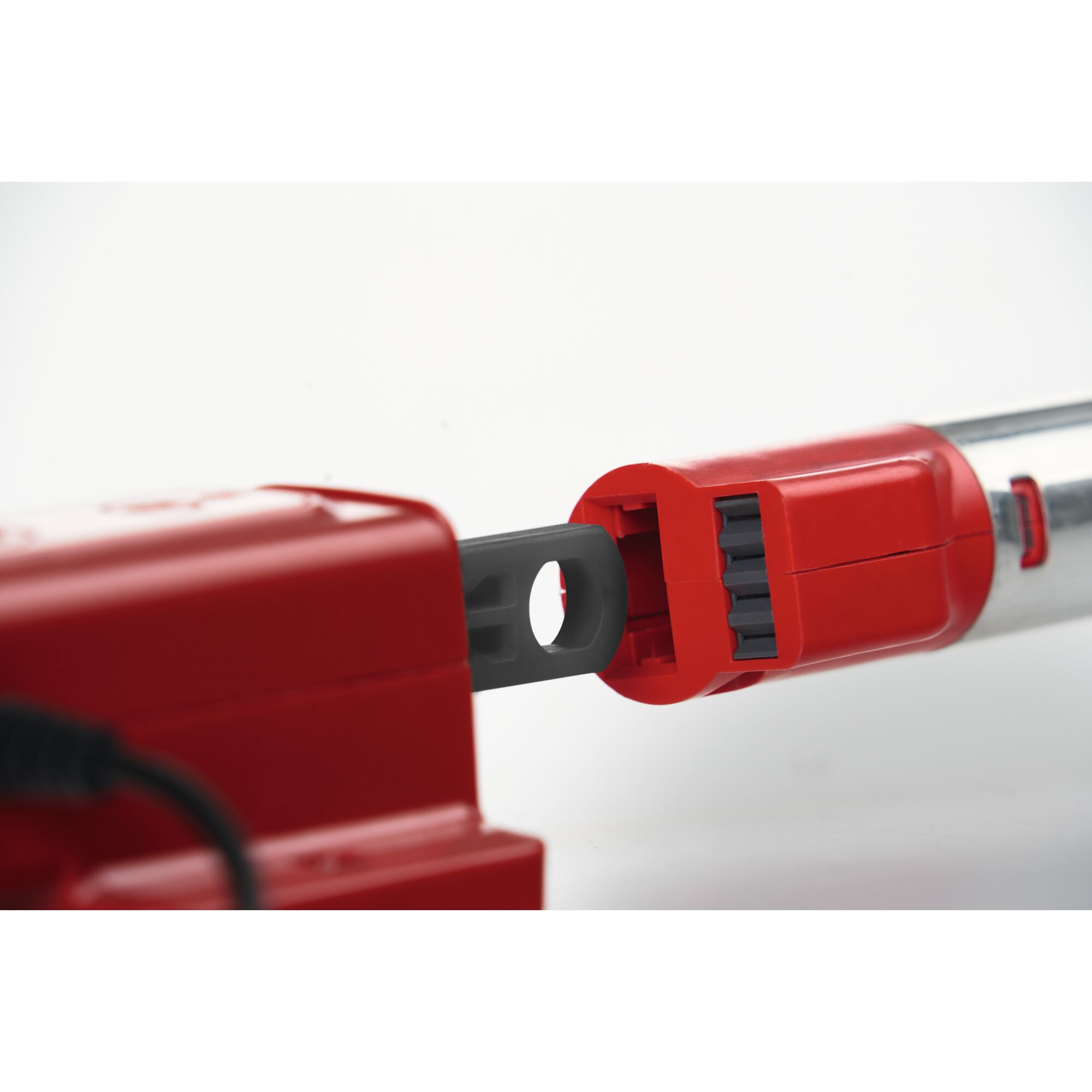Close-up of a red and silver tool with an attachment mechanism, showing a grey connector fitting into a red housing.