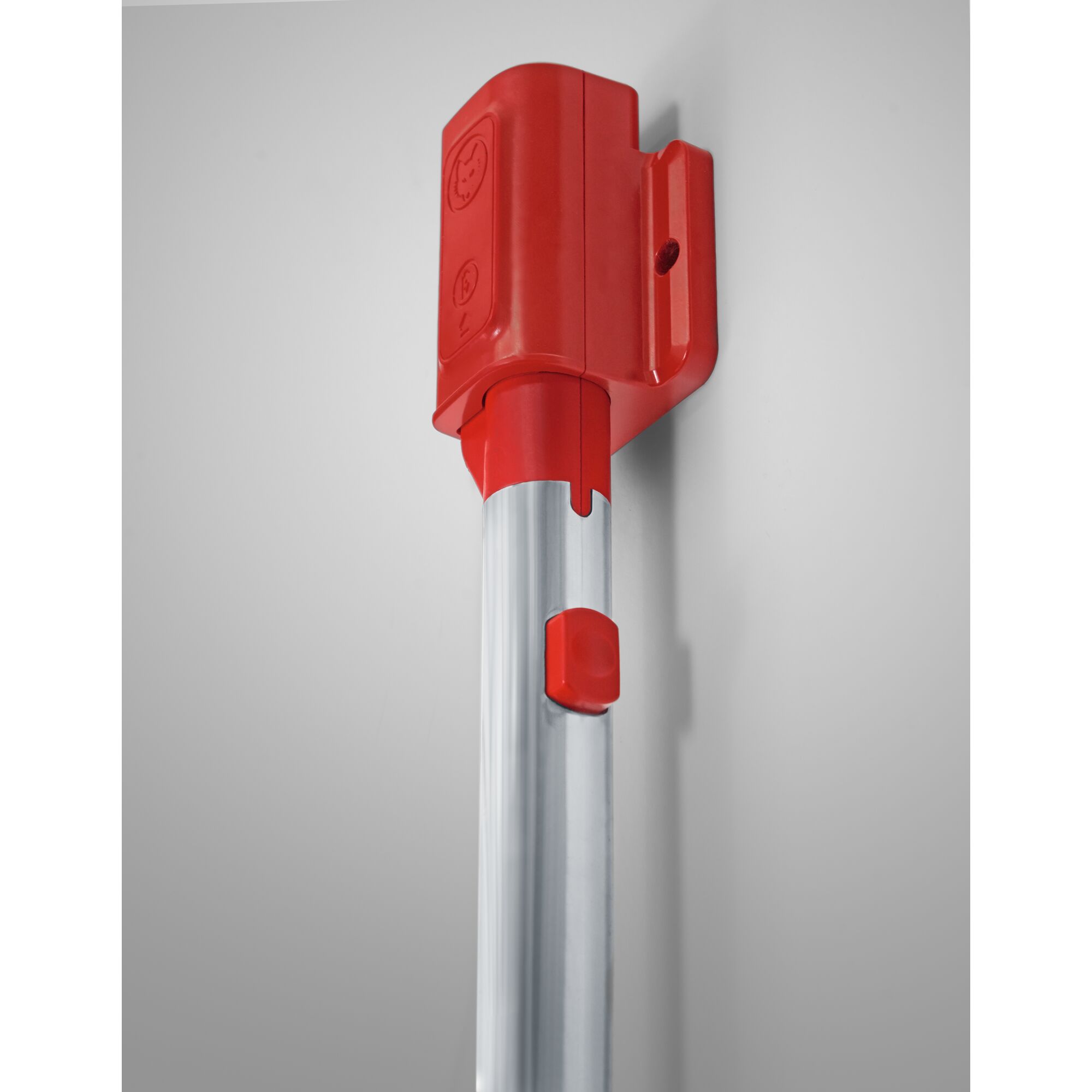 Close-up of a WOLFGarten garden tool handle with a bright red plastic mount attached to a silver metal pole, shown against a light grey wall.