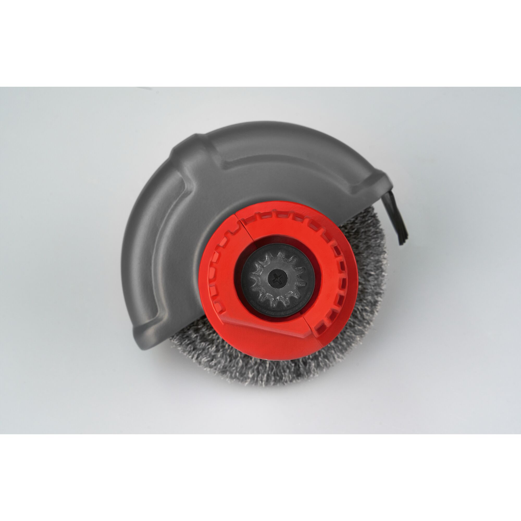 Close-up of a circular brush attachment with grey protective cover and red central hub, designed for gardening or cleaning equipment.