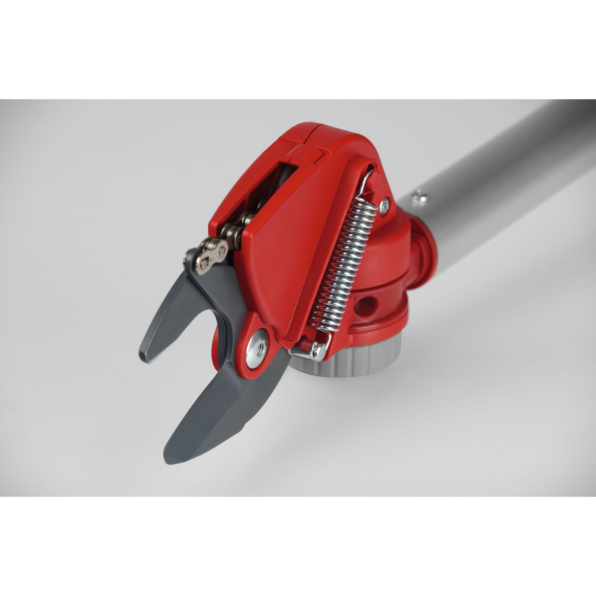 Close-up of a red and grey garden pruning tool head, featuring a spring mechanism and sharp blades, attached to a metal handle.
