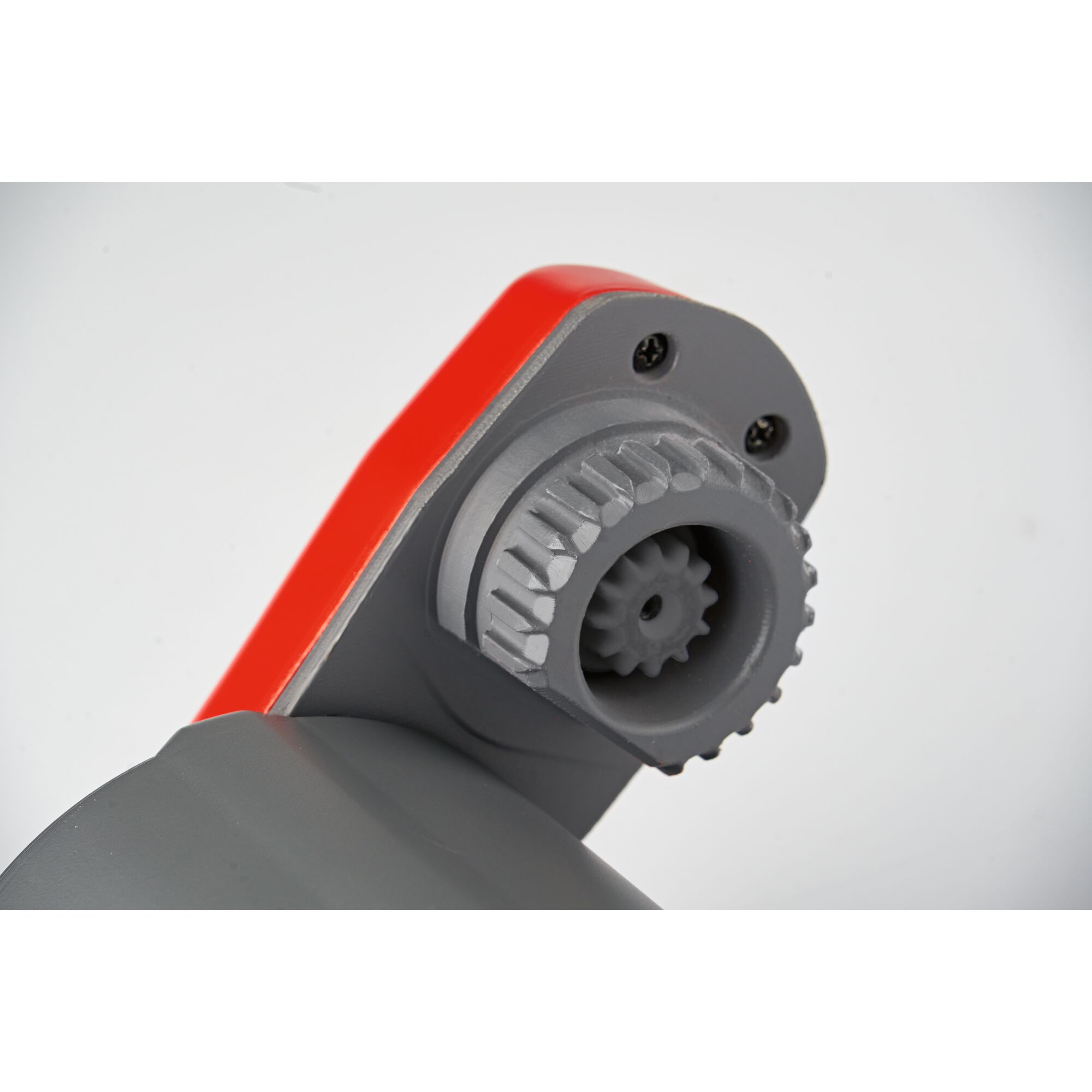 Close-up of a grey and red mechanical connector part with a gear-like fitting and screws, photographed against a plain light background.