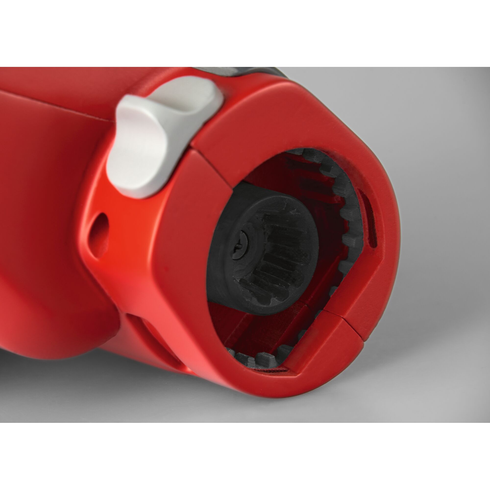 Close-up view of a red and black mechanical connector with a white button, likely part of a garden tool attachment system.