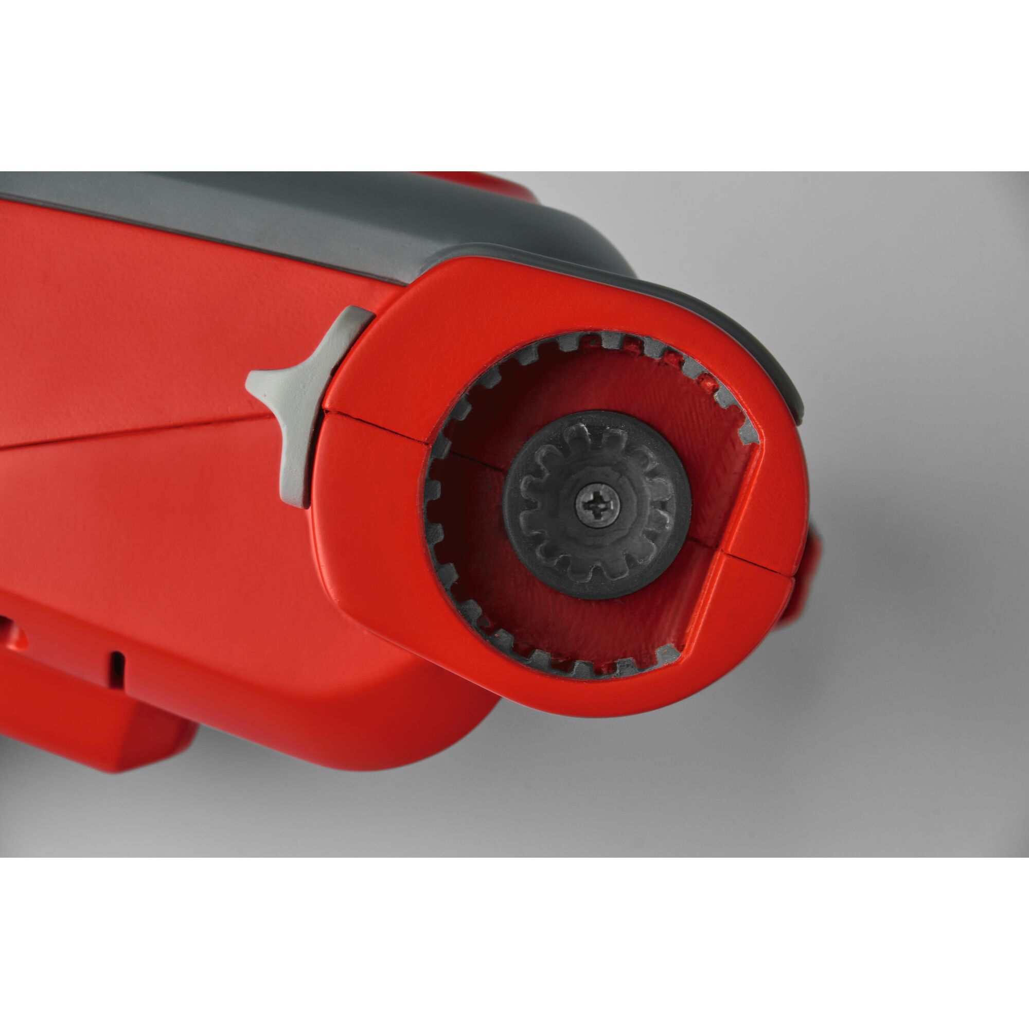 Close-up image of a red and grey mechanical tool, showing a circular opening with gear-like teeth and a central screw.
