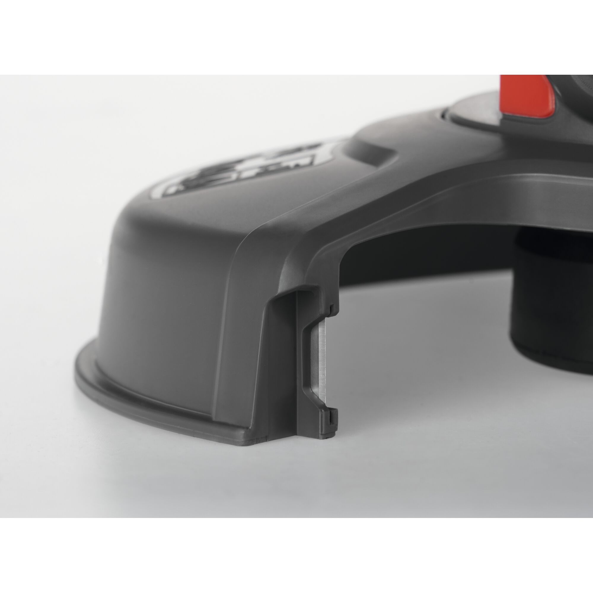 Close-up view of a black and grey plastic component with a metal edge, likely a protective cover or guard for a garden tool.