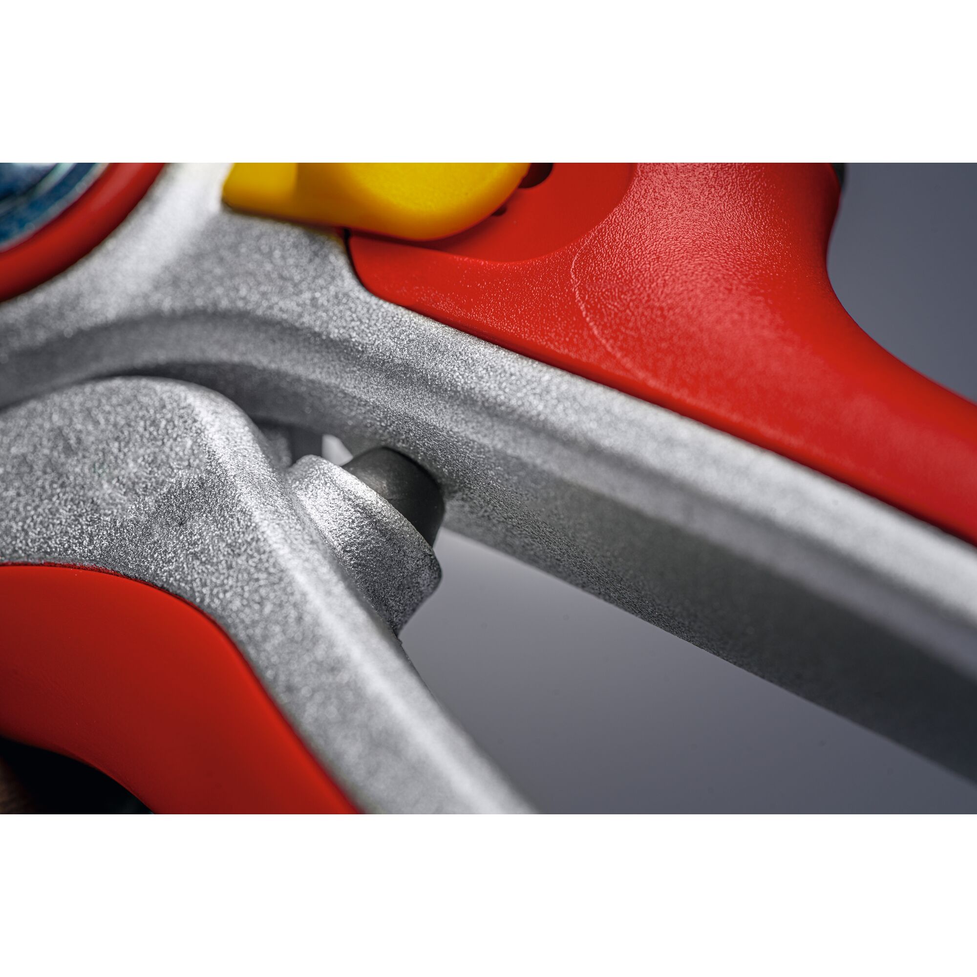 Close-up view of a red and silver garden tool handle with a yellow button, showing details of the textured metal and plastic surfaces.