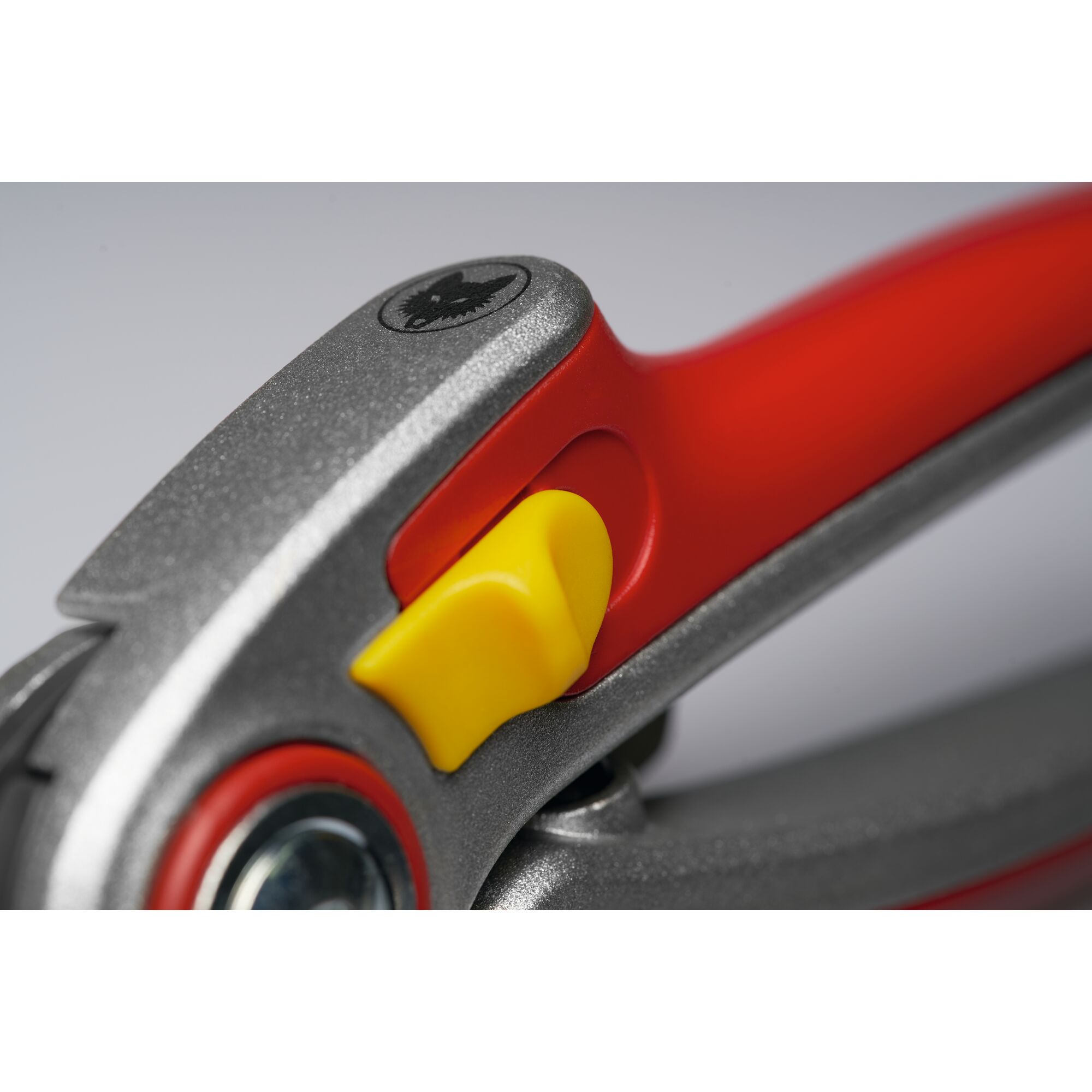 Close-up of a WOLFGarten garden tool handle showing a yellow safety latch and metallic screw, with red and silver accents.