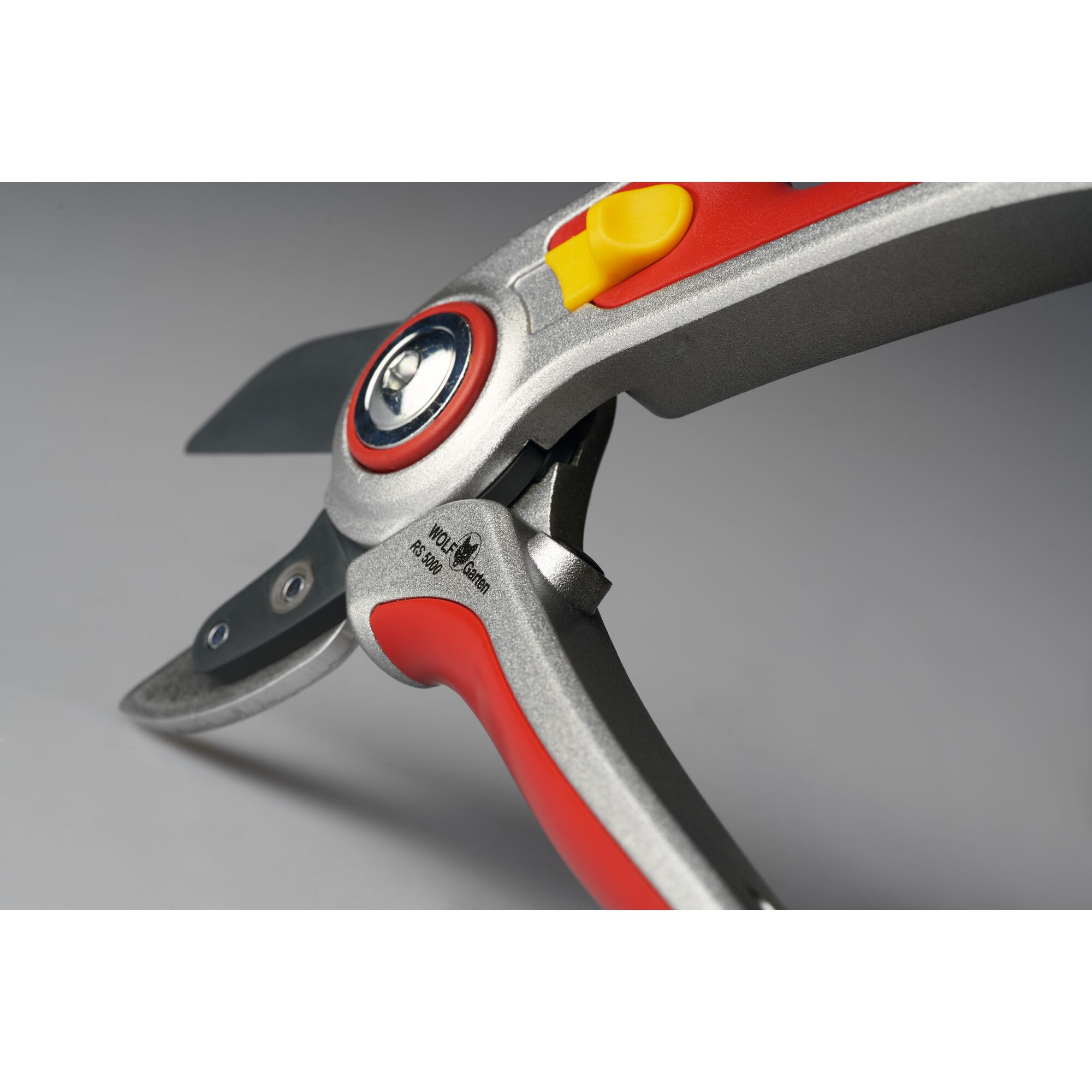 Close-up view of a WOLF-Garten pruning shear with red and silver handles and a yellow safety lock, designed for garden use.