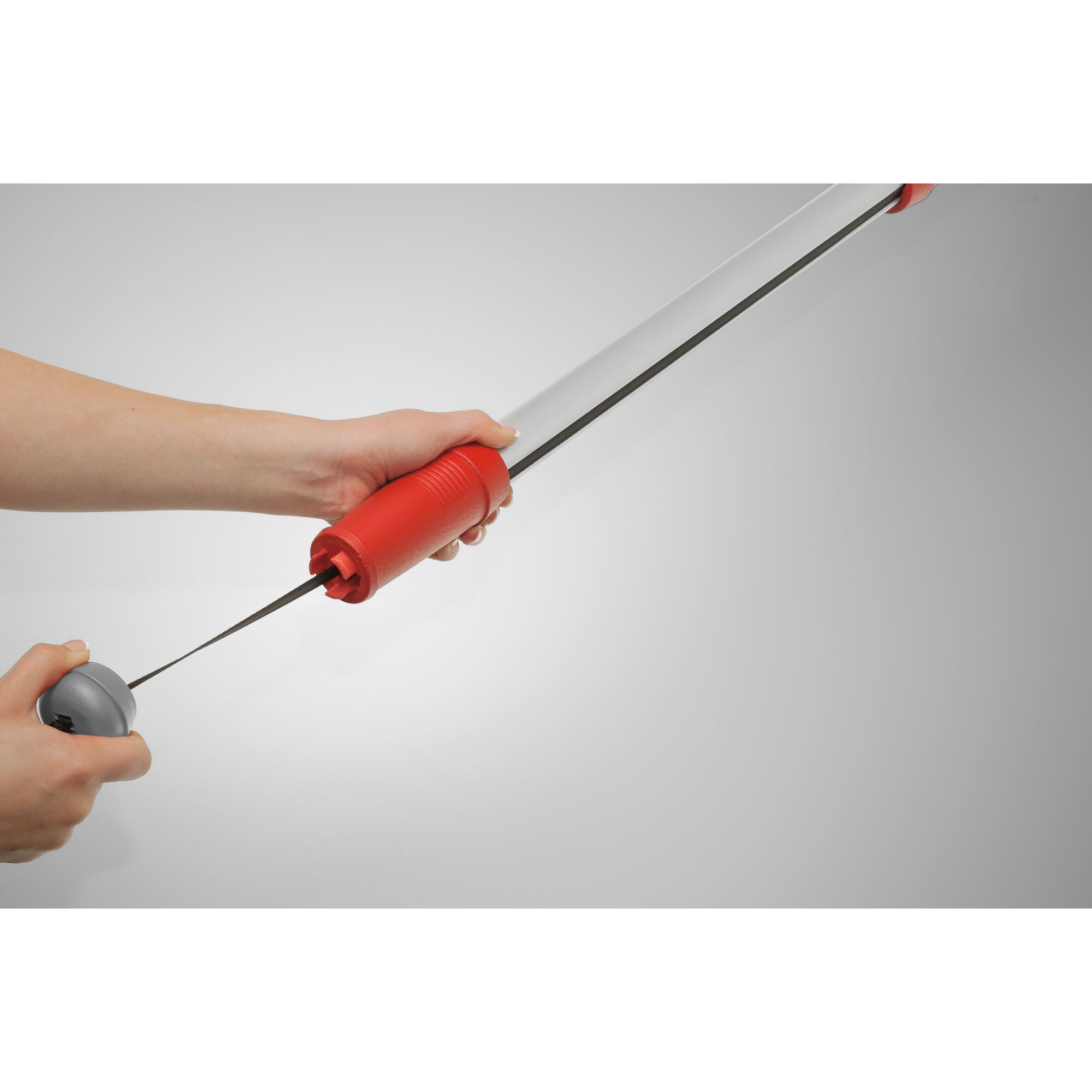 Close-up of hands holding and adjusting a telescopic garden tool with a red handle and silver shaft, featuring a cable mechanism.
