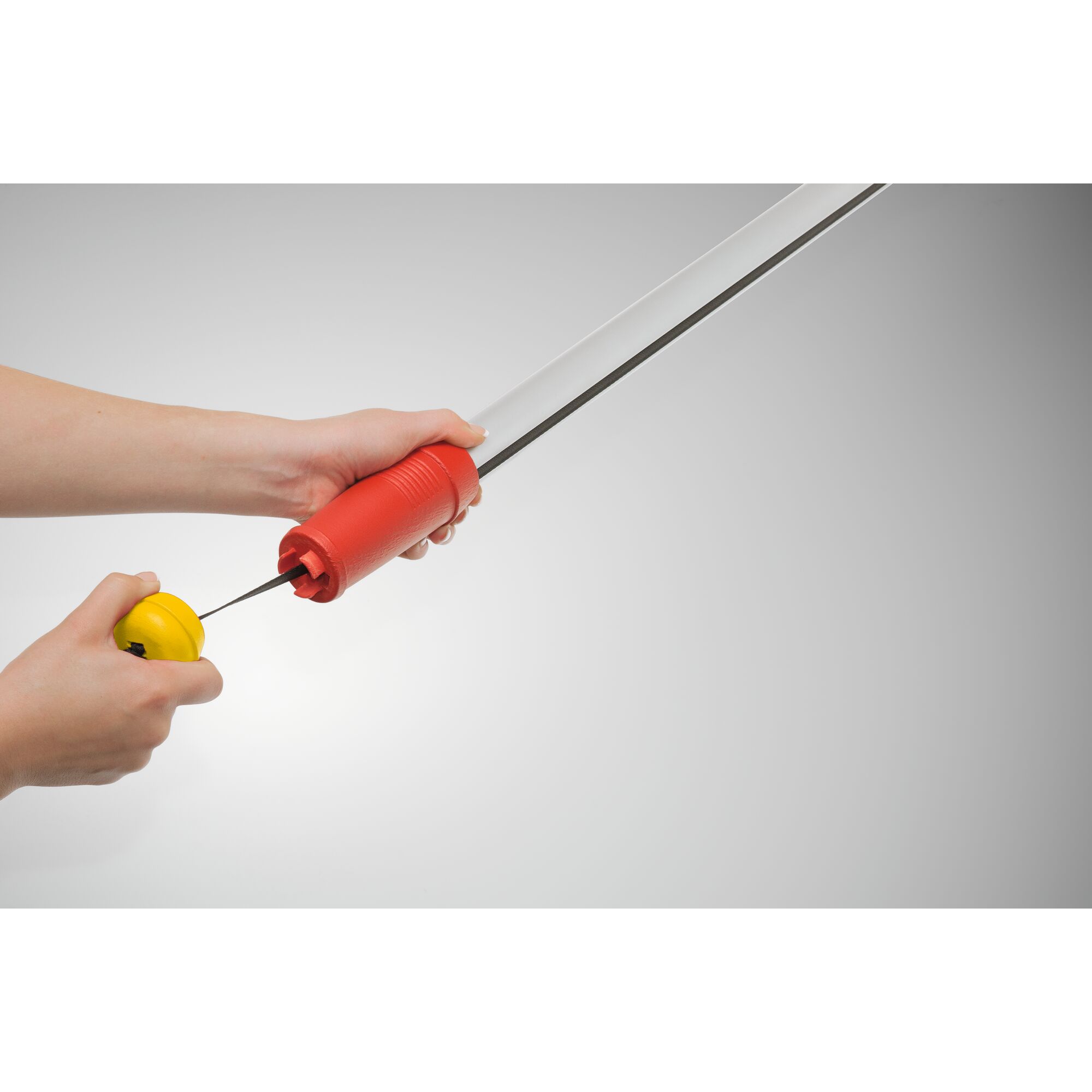 Close-up of hands attaching a WOLF-Garten gardening tool handle with a red grip and a yellow connecting mechanism.
