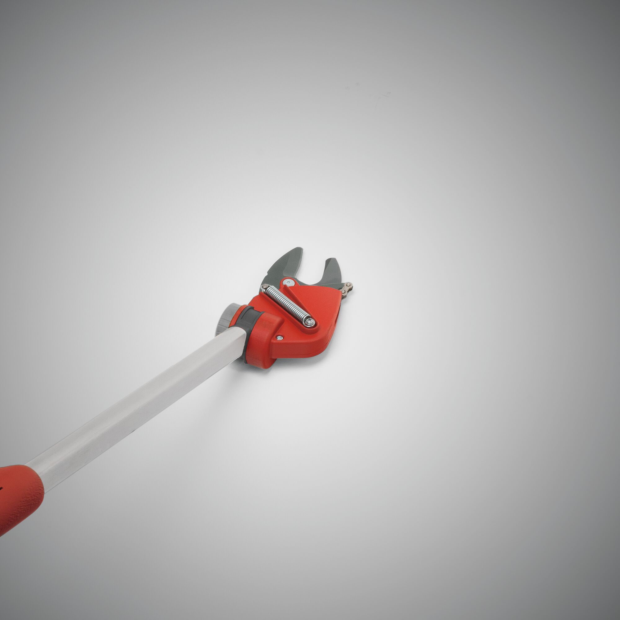 A close-up view of a red and silver telescopic pruning tool with a cutting blade, used for gardening and trimming branches.