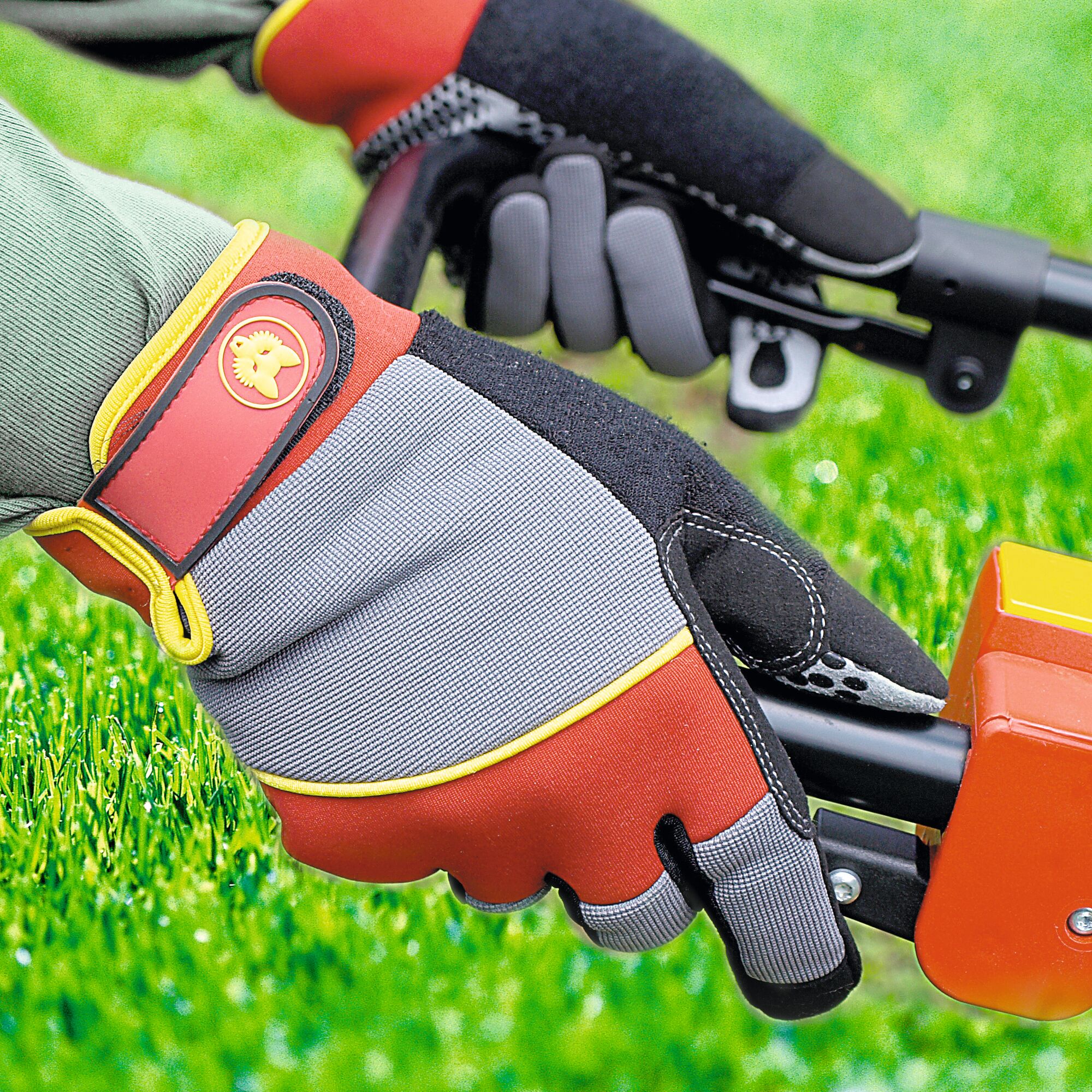 Close-up of a person wearing protective gardening gloves from WOLFGarten operating a garden tool on green grass.